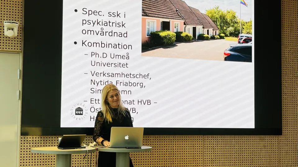 Kvinna står och föreläser framför sin powerpoint