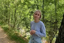 Bild på kvinna i tröja och jeans i skogen