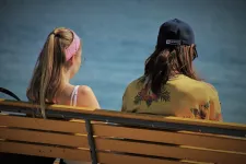 Ung kvinna och man vid strand på bänk